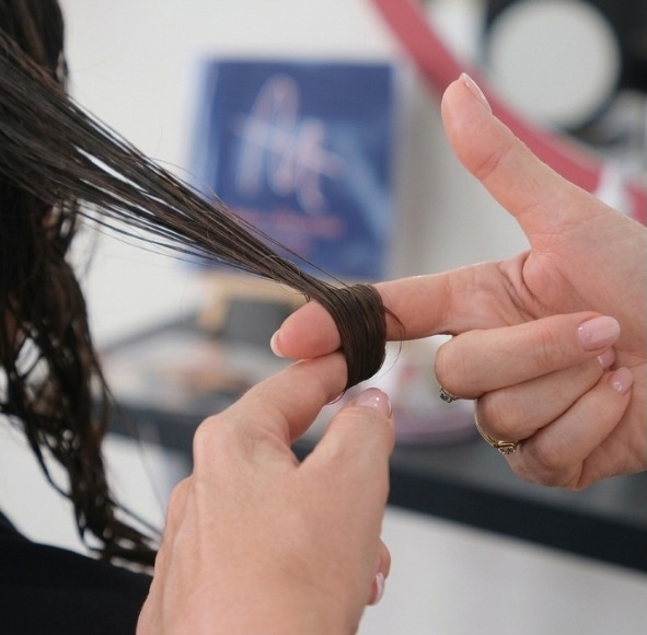 Mains d’une coiffeuse travaillant une mèche de cheveux dans le salon